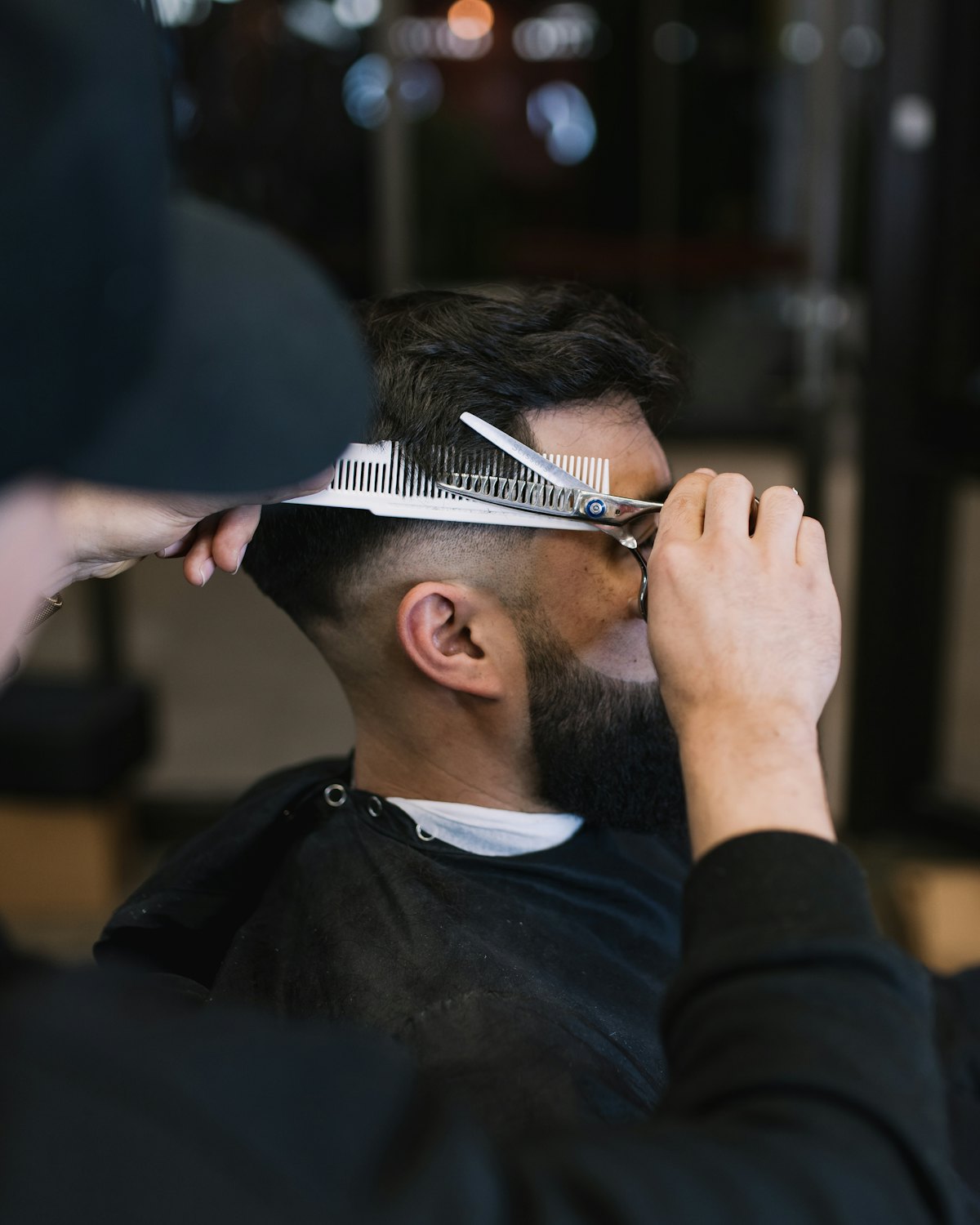 Barber cutting hair with scissors